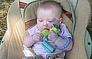 Adriana is chewing on a toy while watching the kids have fun on the slip-and-slide